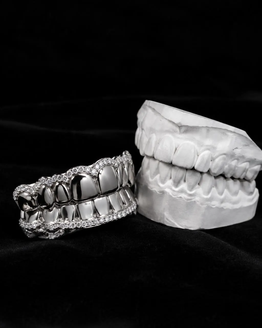 18K white gold grillz edged with lab-grown diamonds next to a plaster dental model