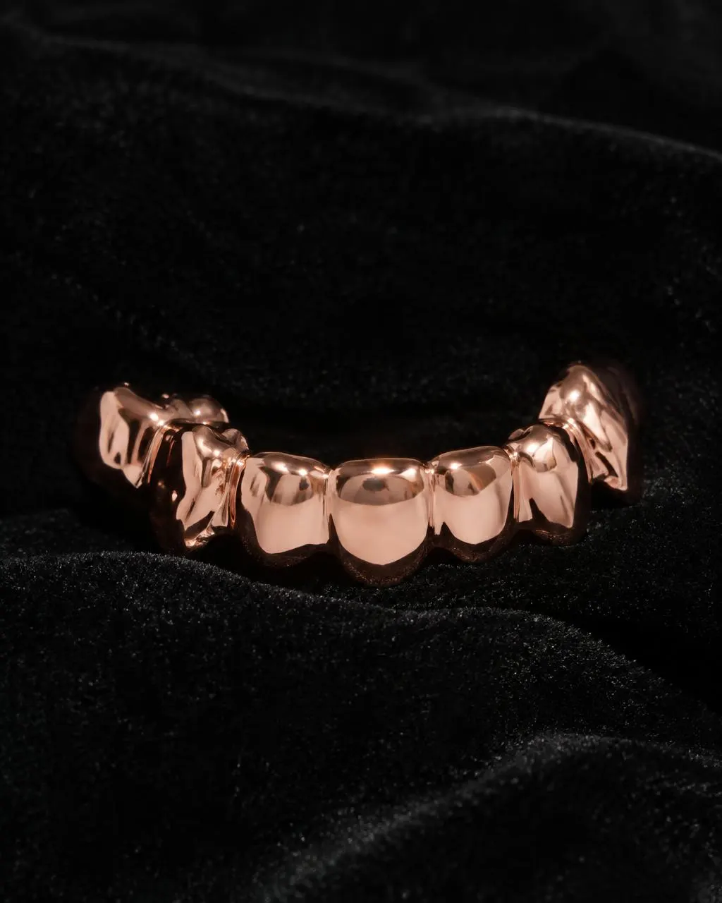 Rose gold grillz for the bottom teeth on black velvet